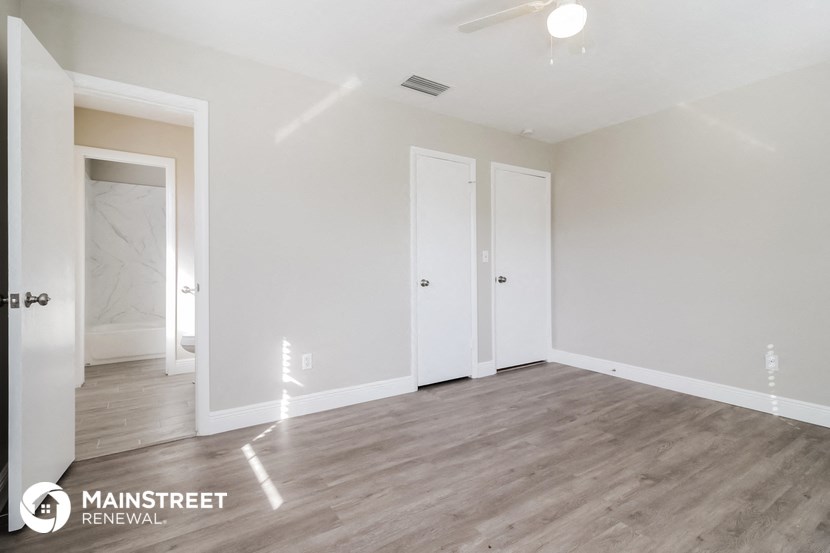 the spacious living room with white walls and wood flooring