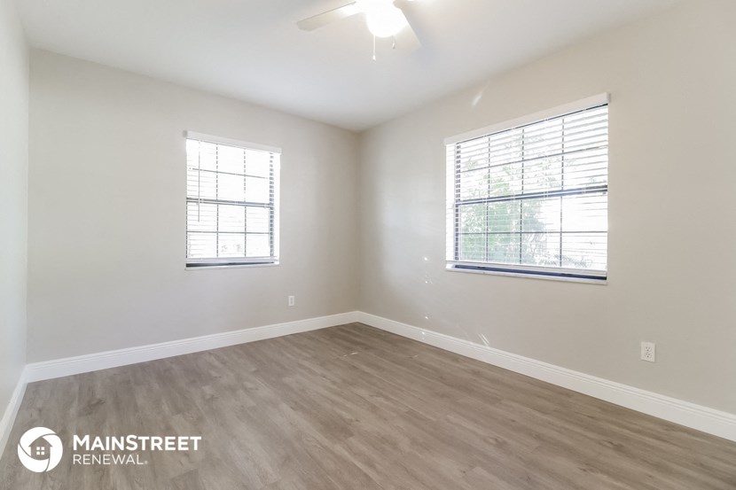 the spacious living room with wood flooring and two windows