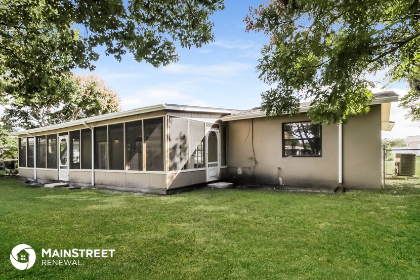 the exterior of a white house with large windows and a lawn