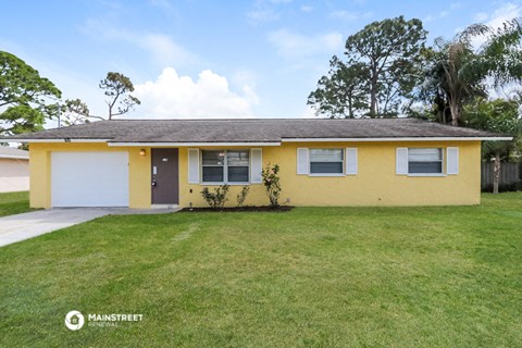 a yellow house with a lawn and a white garage door