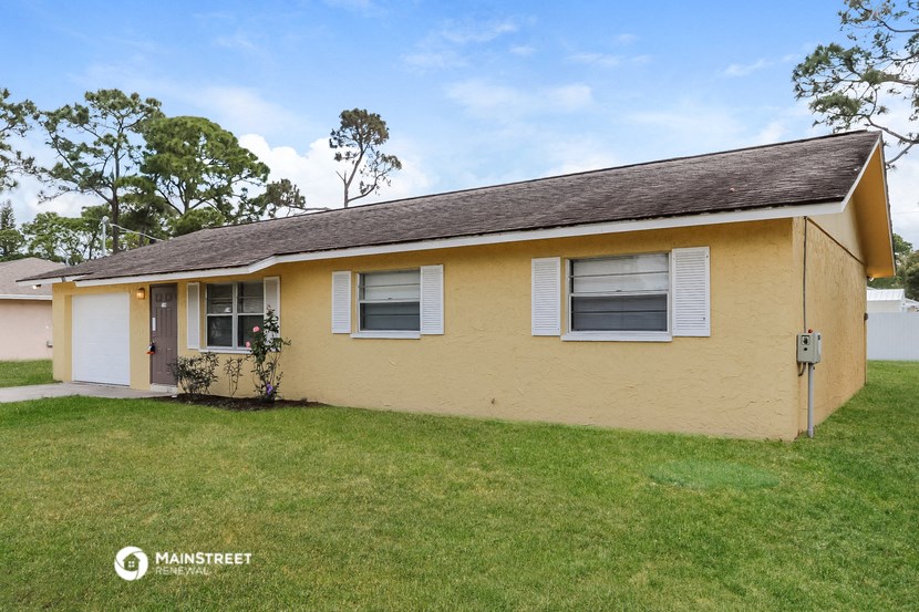 the front of a yellow house with a yard and grass