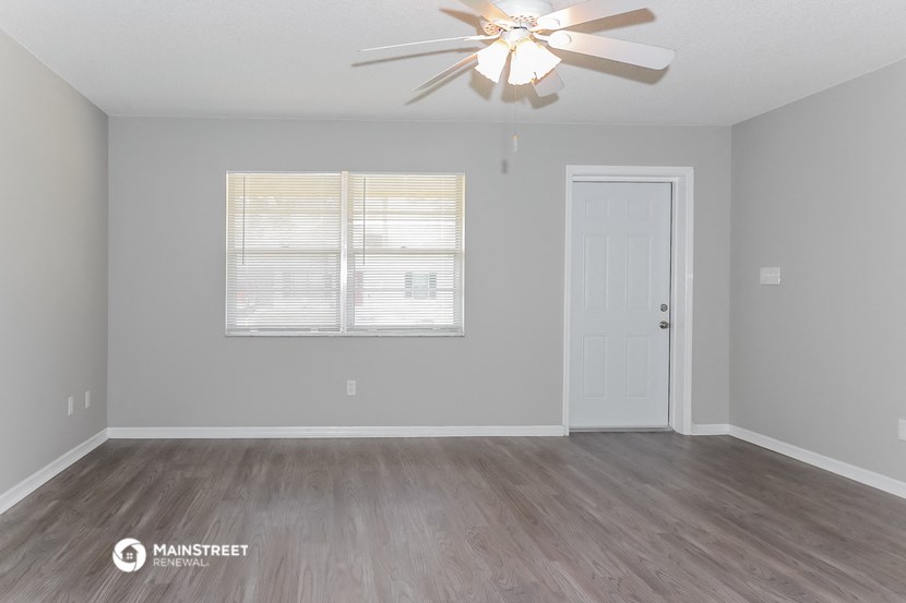 the living room of an empty house with a ceiling fan