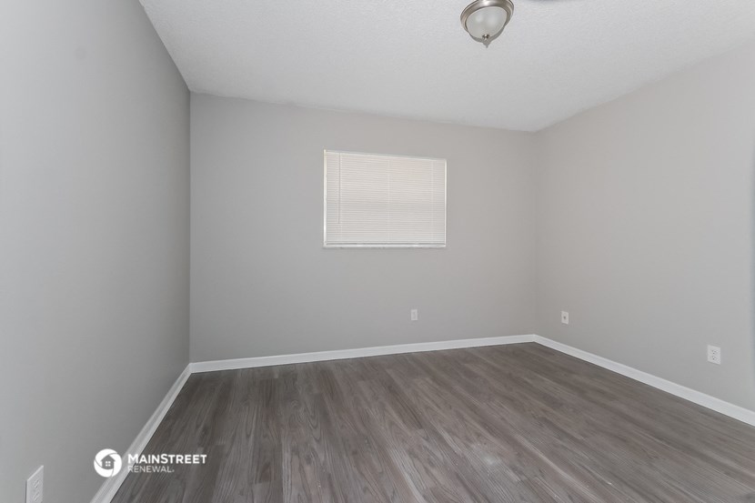 a bedroom with wood floors and grey walls and a window