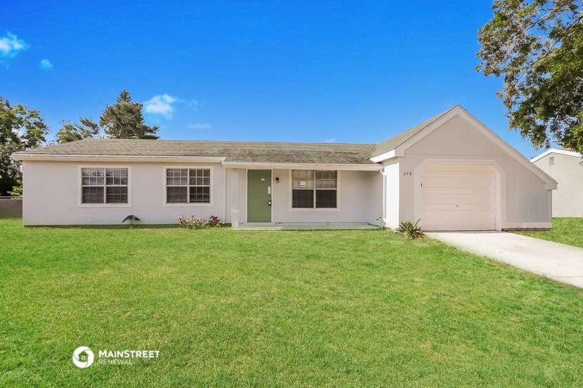 a white house with a green lawn and a white garage door