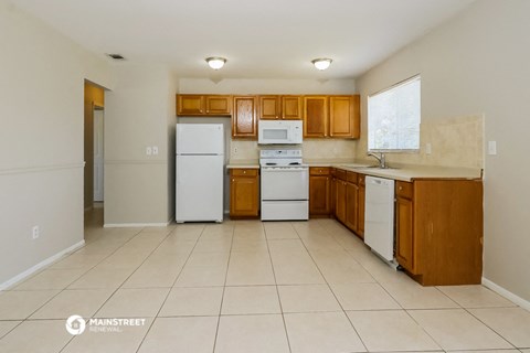 a kitchen with white appliances and wooden cabinets and tiled floors