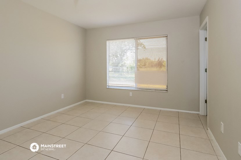 an empty living room with a window and a tiled floor
