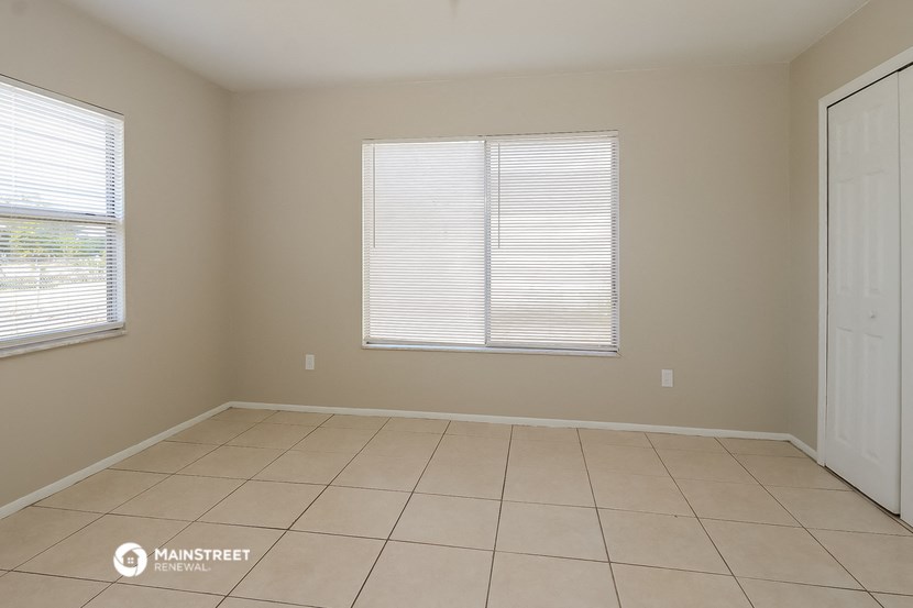 an empty living room with two windows and a tiled floor