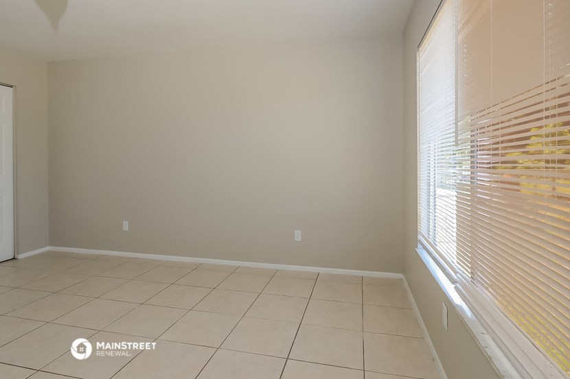 an empty living room with a large window and a tiled floor