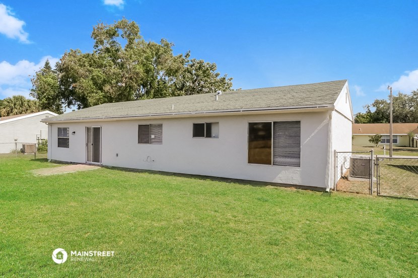 a small white house with a grass yard and a fence