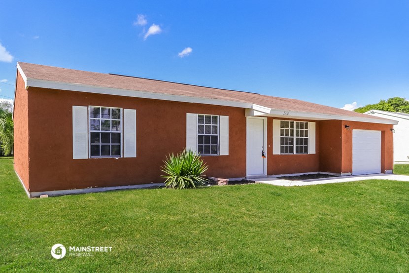 a small brick house with a lawn in front of it