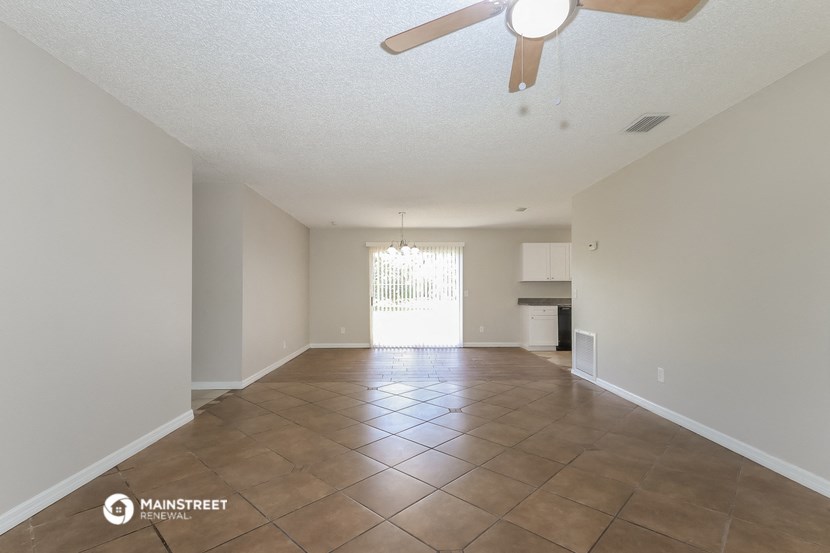 a spacious living room with tile flooring and a ceiling fan