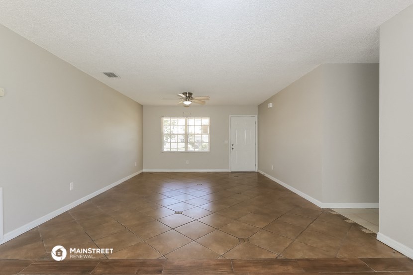 the spacious living room with tile flooring and a ceiling fan