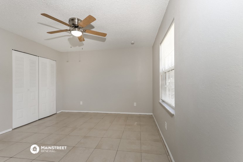 an empty living room with a ceiling fan and a window