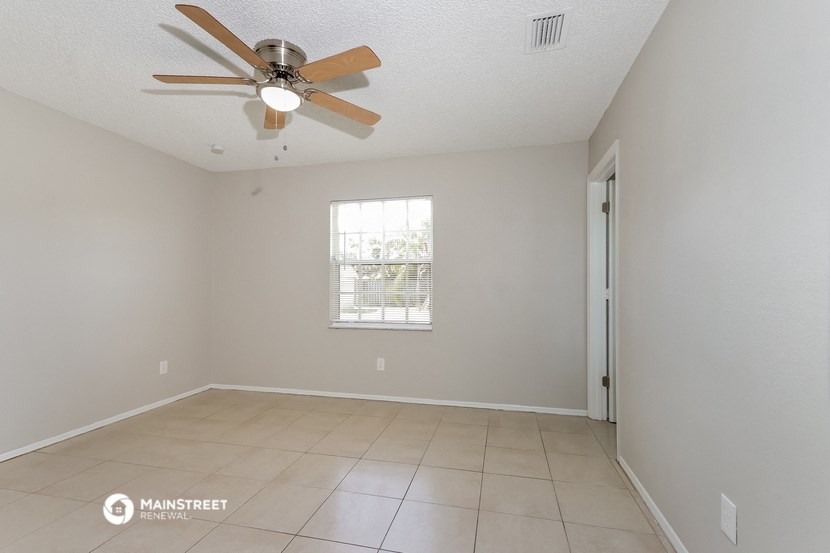 the spacious living room with ceiling fan and tiled floor