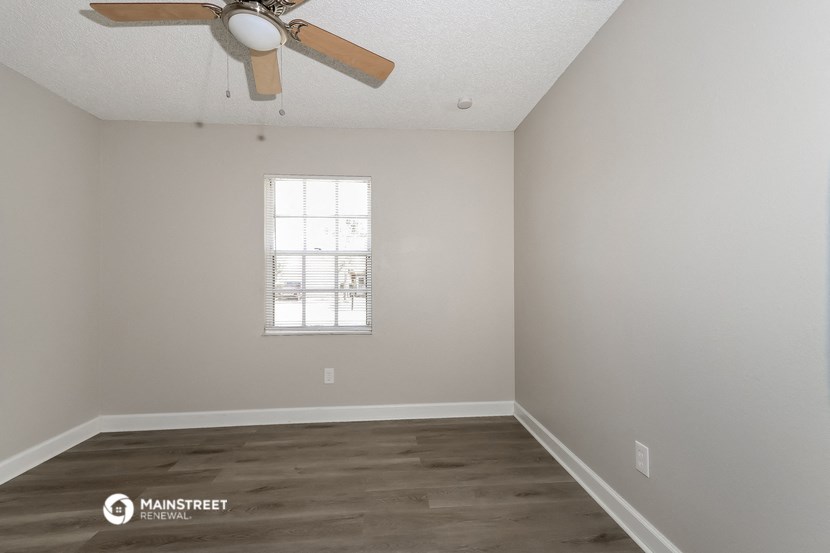 an empty room with a ceiling fan and a window