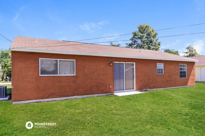 the front of a brick house with a lawn and a door