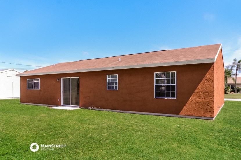 a red brick house with a grassy yard and a blue sky