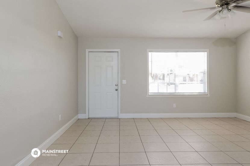 an empty living room with a white door and a window