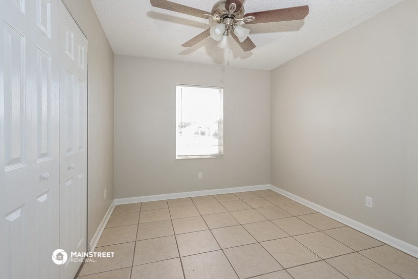 a empty living room with a ceiling fan and a closet