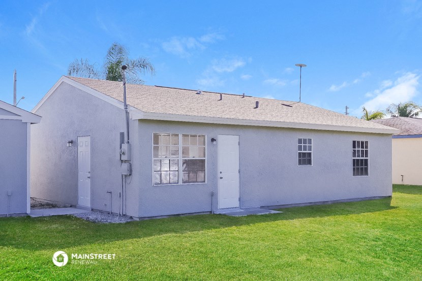 the front of a white house with a yard and grass