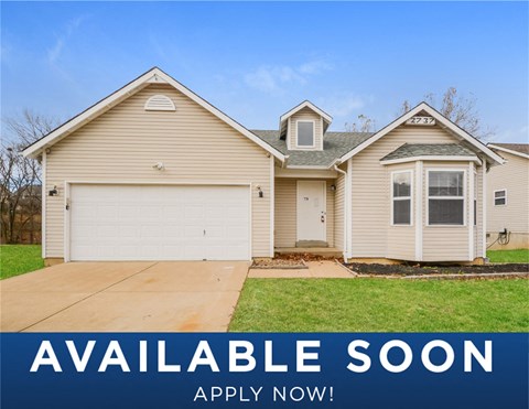 a tan house with a green lawn and a blue sky