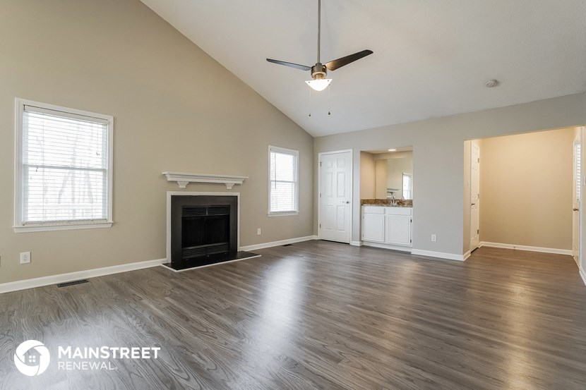 an empty living room with a fireplace and a ceiling fan