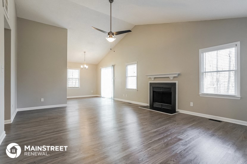 an empty living room with a fireplace and a ceiling fan