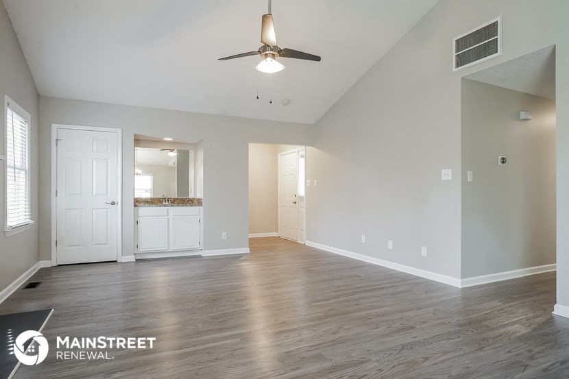 an empty living room with a ceiling fan and a bathroom