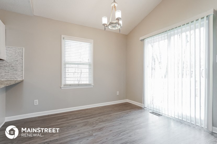 an empty living room with a large window and wood floors