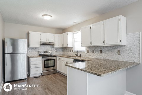 a kitchen with white cabinets and a marble counter top