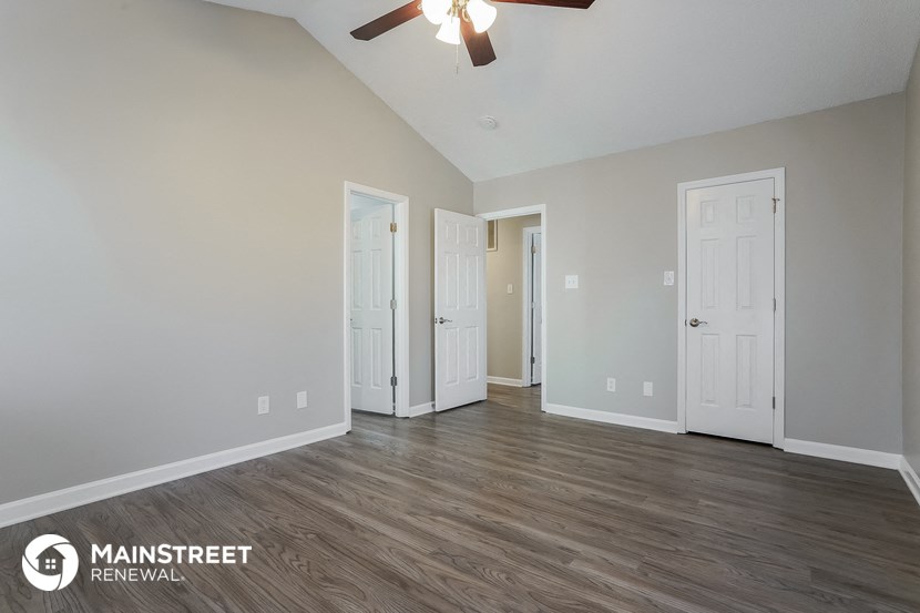 an empty living room with wood flooring and a ceiling fan