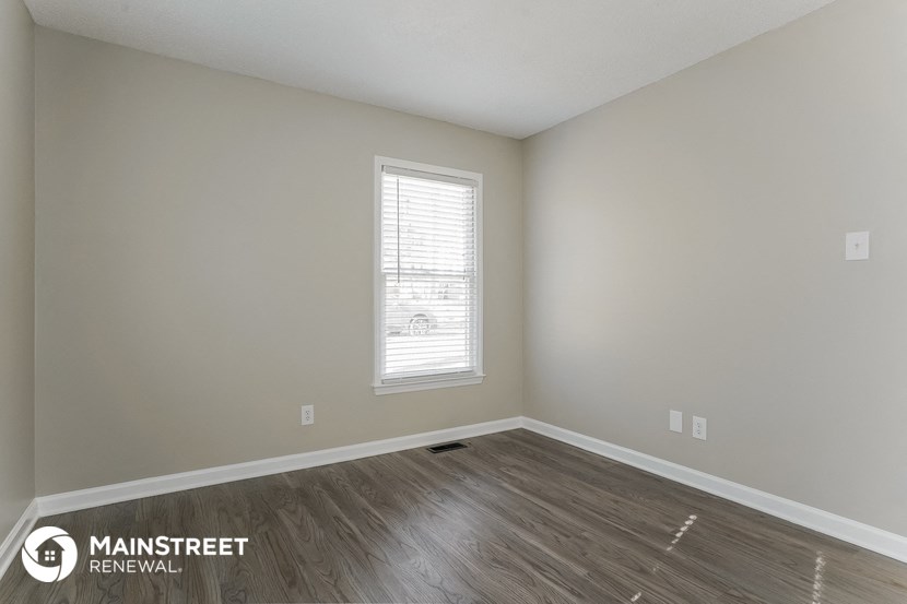 the living room of an apartment with wood flooring and a window