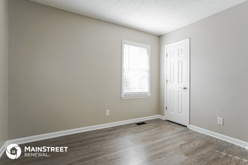 the living room of an apartment with wood flooring and a white door