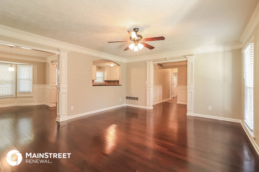 an empty living room with wood floors and a ceiling fan
