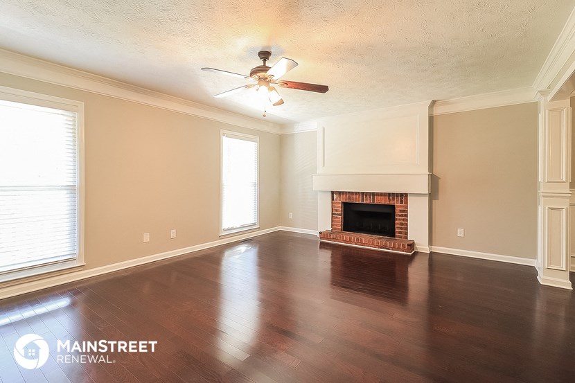 a living room with a fireplace and a ceiling fan