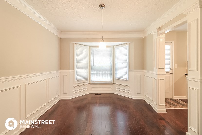 a dining room with wood floors and a bay window