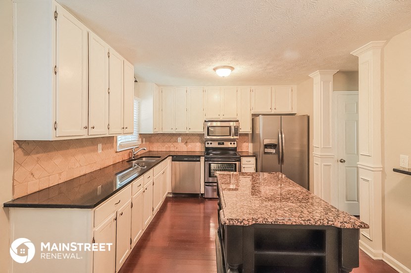 a kitchen with white cabinets and granite counter tops and stainless steel appliances
