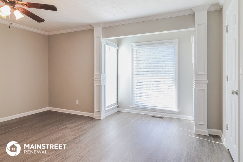 a living room with wood floors and a window and a ceiling fan