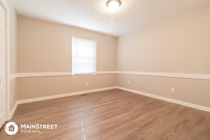 the spacious living room with hardwood flooring and a window