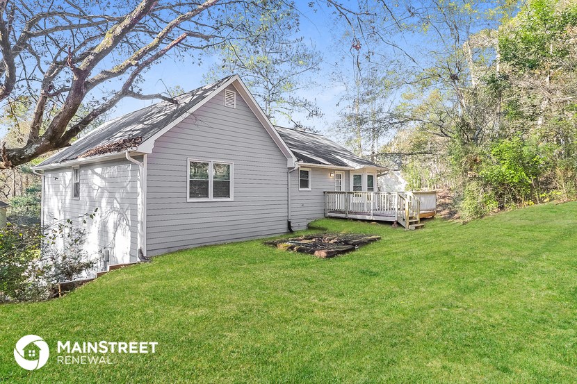 a small gray house with a yard and a deck