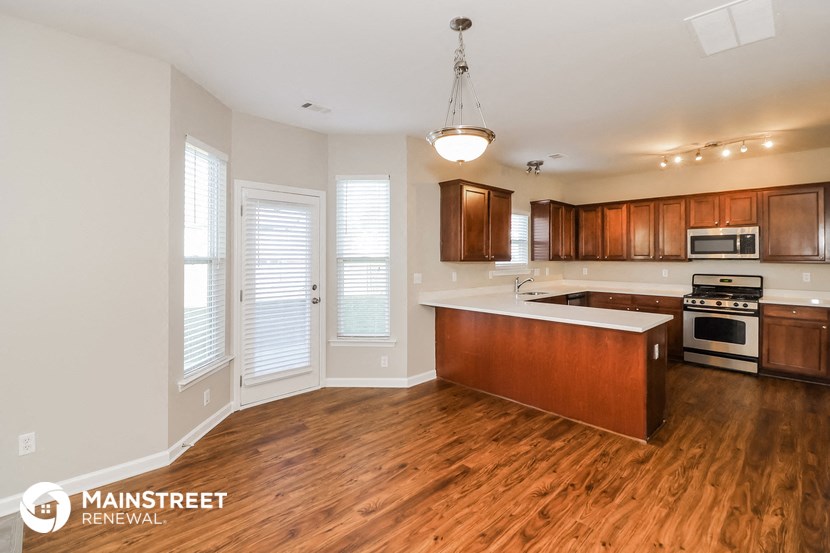 a kitchen with wood flooring and wooden cabinets and a white counter top