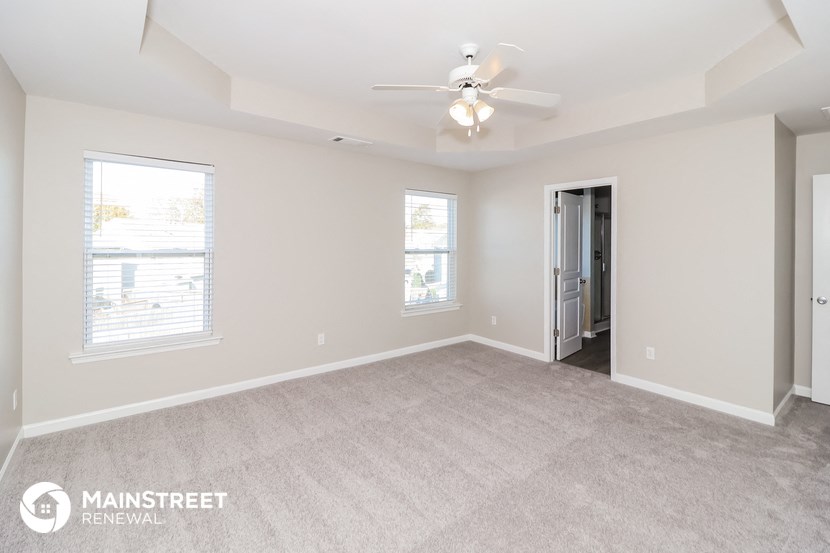 the spacious living room with carpeting and a ceiling fan