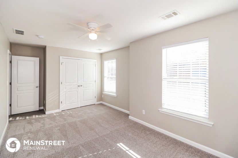 the master bedroom has a carpeted floor and a ceiling fan