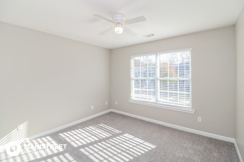 an empty room with a ceiling fan and a window