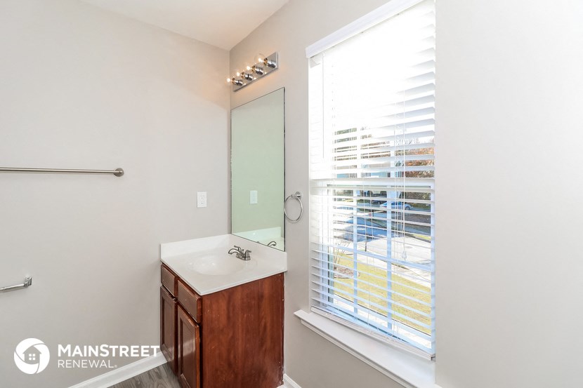 a bathroom with a large window and a sink and a mirror