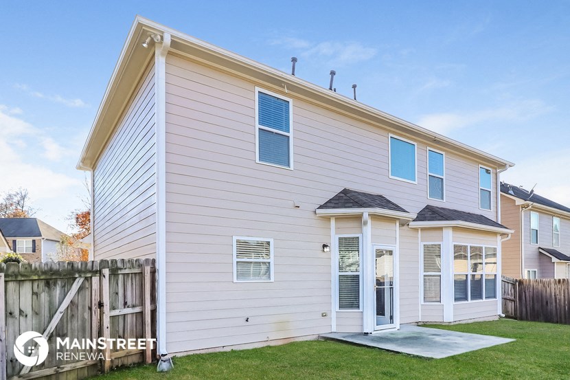 the outside of a white house with a yard and a wooden fence