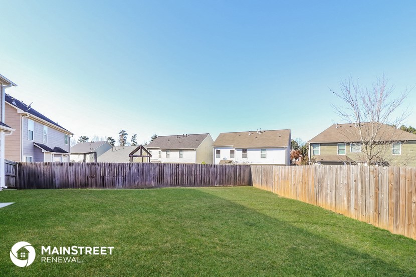 a backyard with a fence and houses in the background