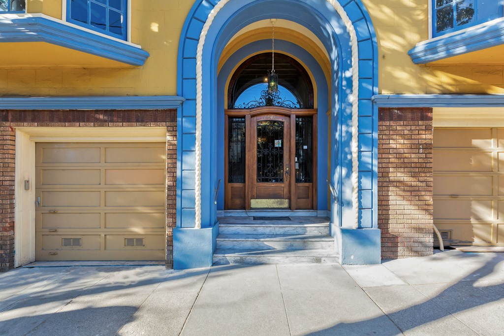 the front door of a blue and yellow house with a garage door