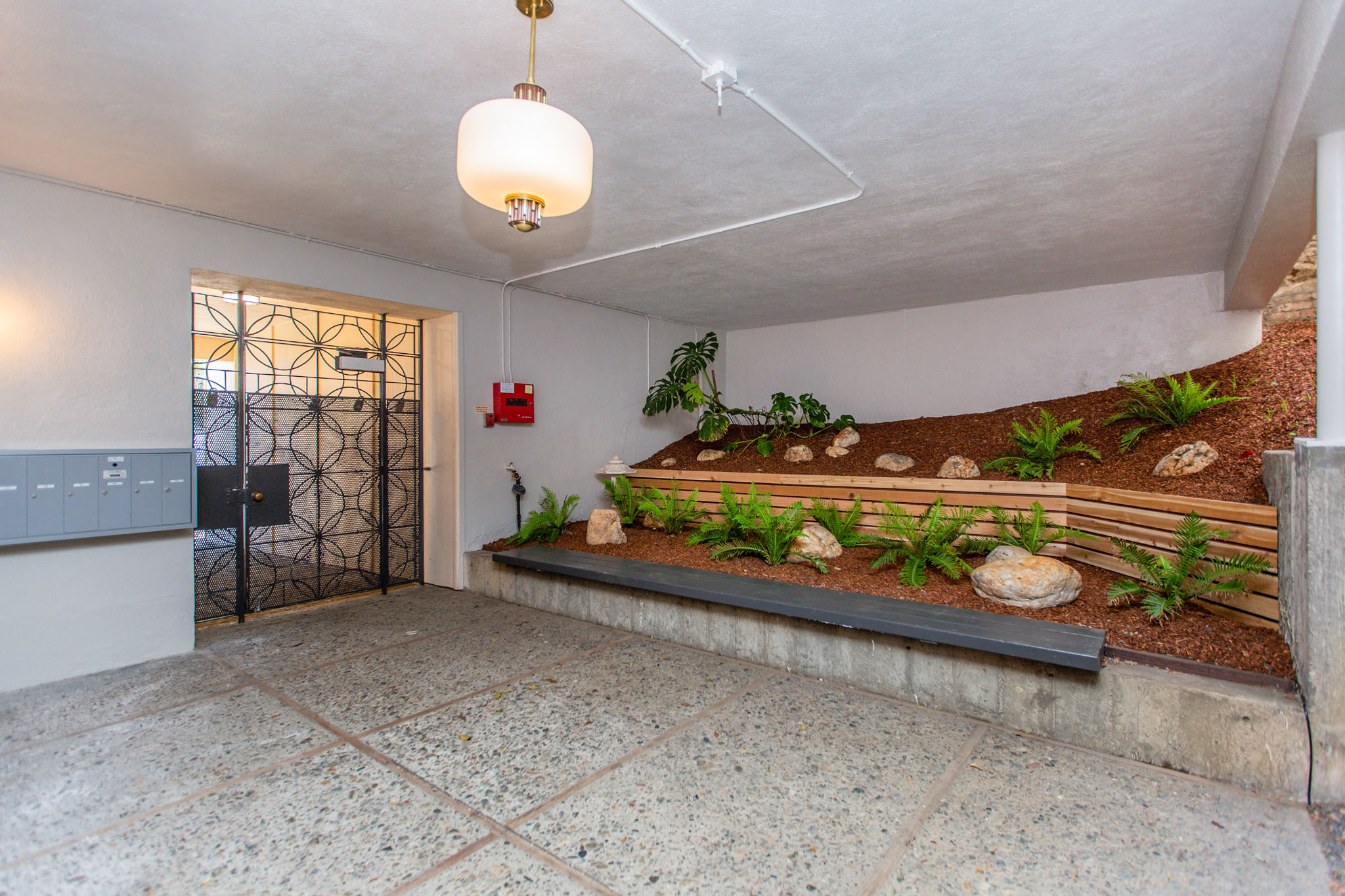 A room with a small garden and a hanging light fixture.