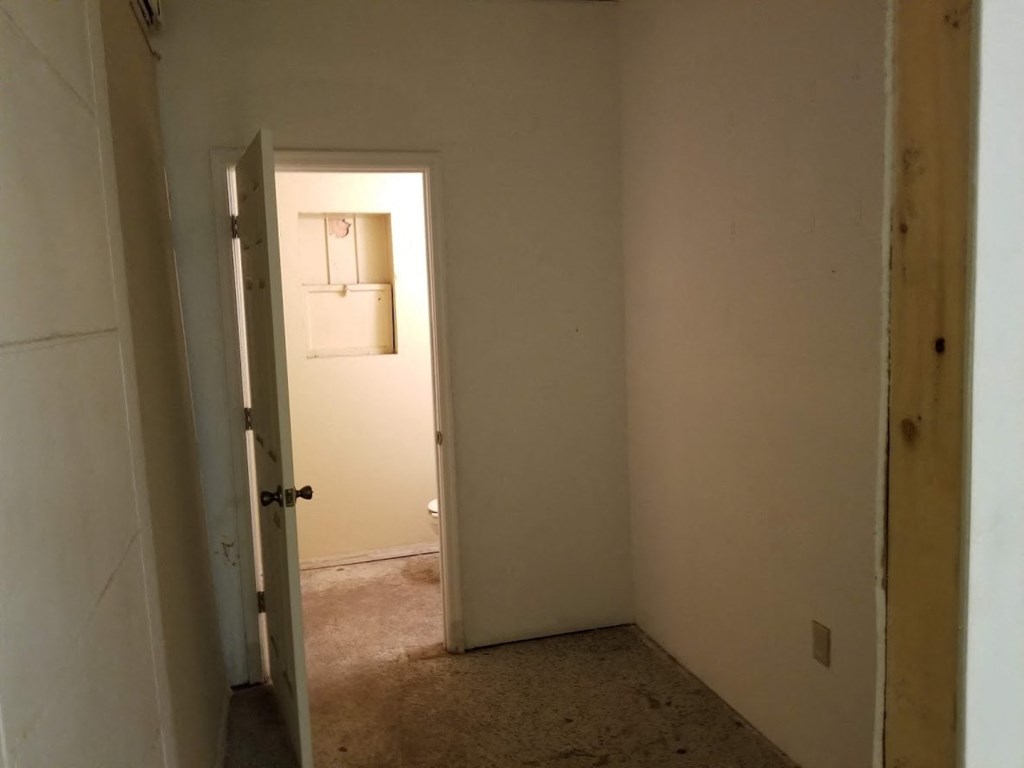 a hallway with a door to a bathroom and a closet